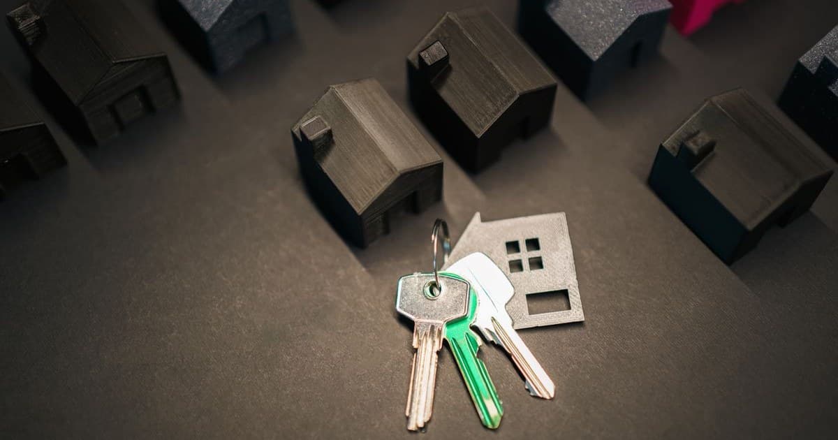Chaveiro em formato de casa ao lado de miniaturas de casas sobre uma mesa, representando o empréstimo com garantia de imóvel