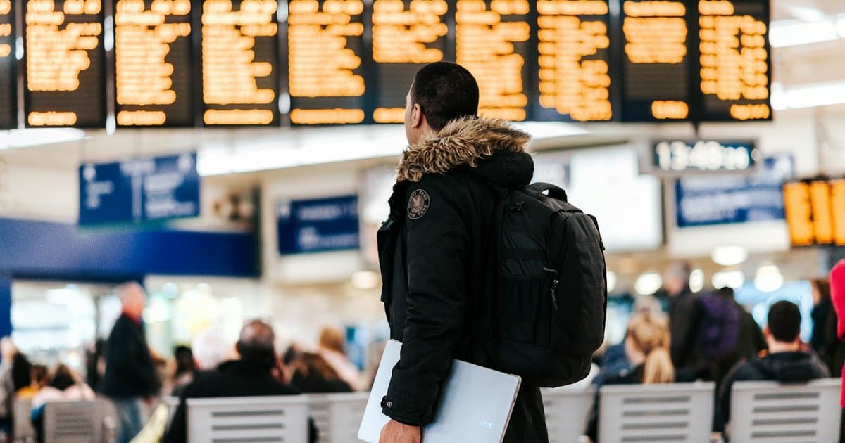 Passageiro com mala e passaporte em aeroporto, representando a contratação de um seguro viagem